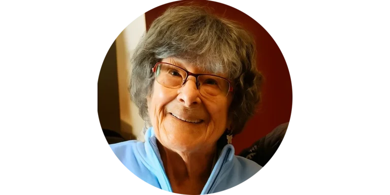 Lächelnde Seniorin mit Brille in blauer Jacke – eine liebe Kundin von Mia Oppermanns Seniorenassistenz.